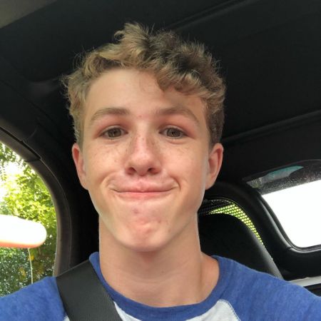 Ethan Wacker in a blue-white t-shirt poses in his car.